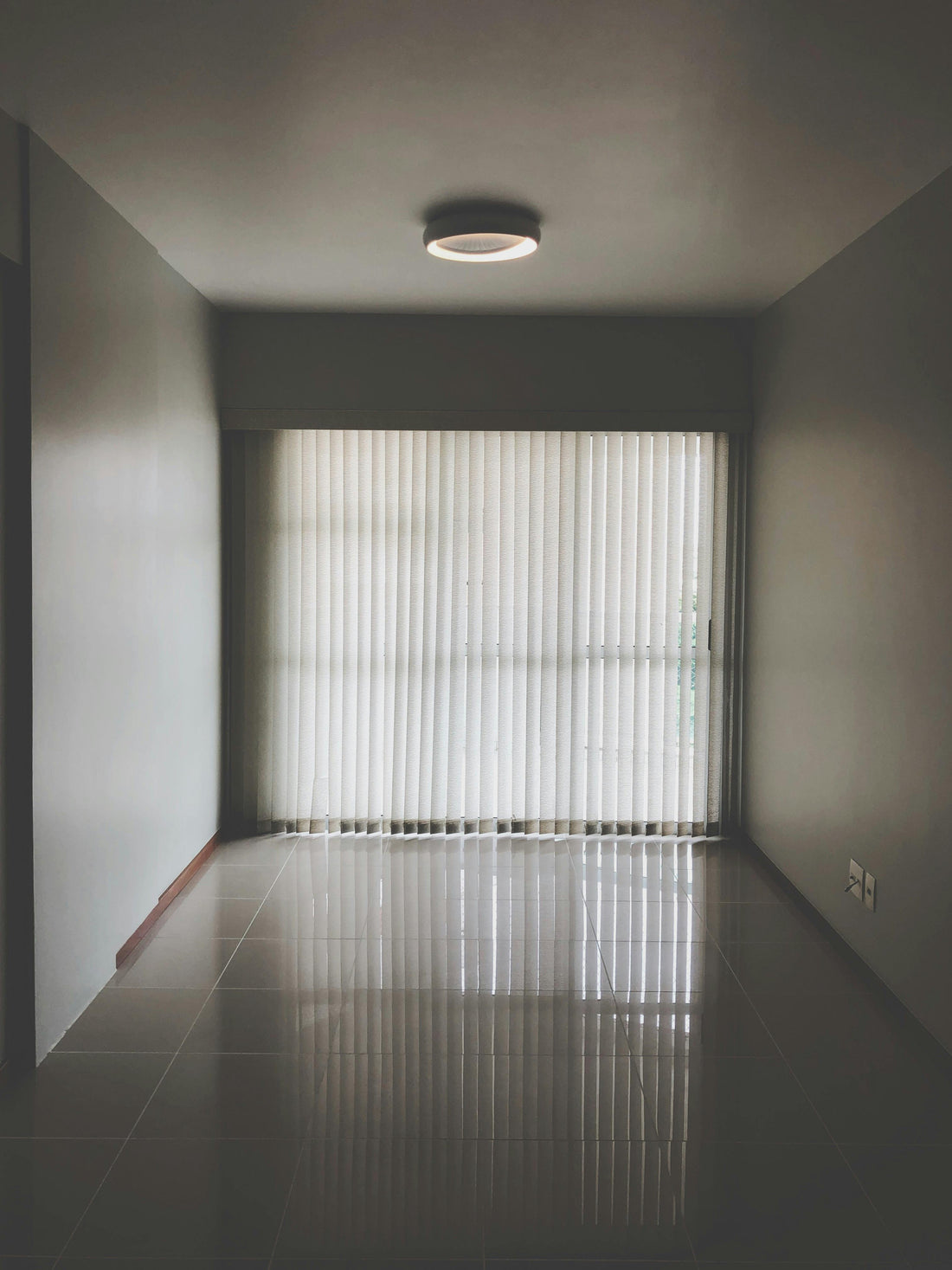 Ceiling light fixture in an empty room with light streaming through the blinds