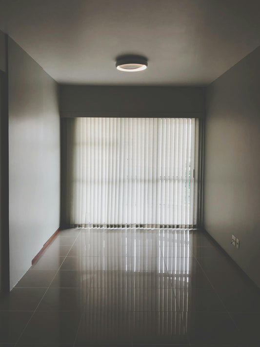 Ceiling light fixture in an empty room with light streaming through the blinds